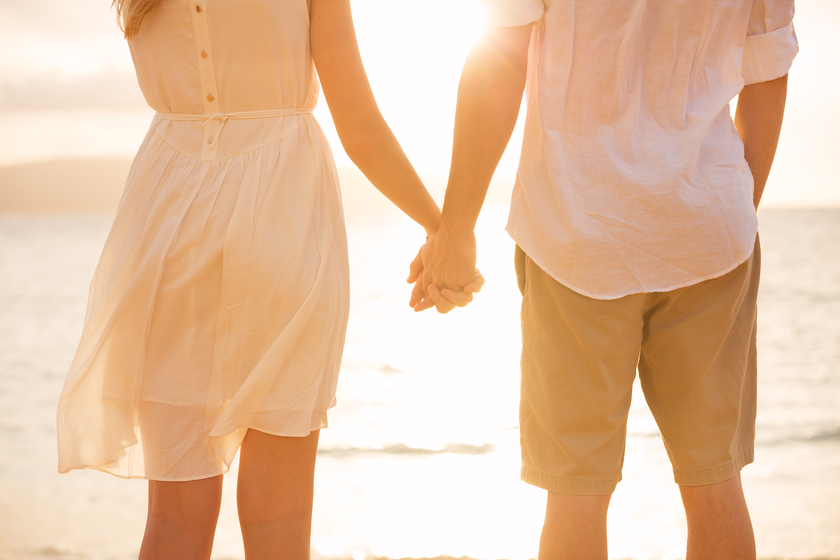 Image of man and woman holding hands on beach